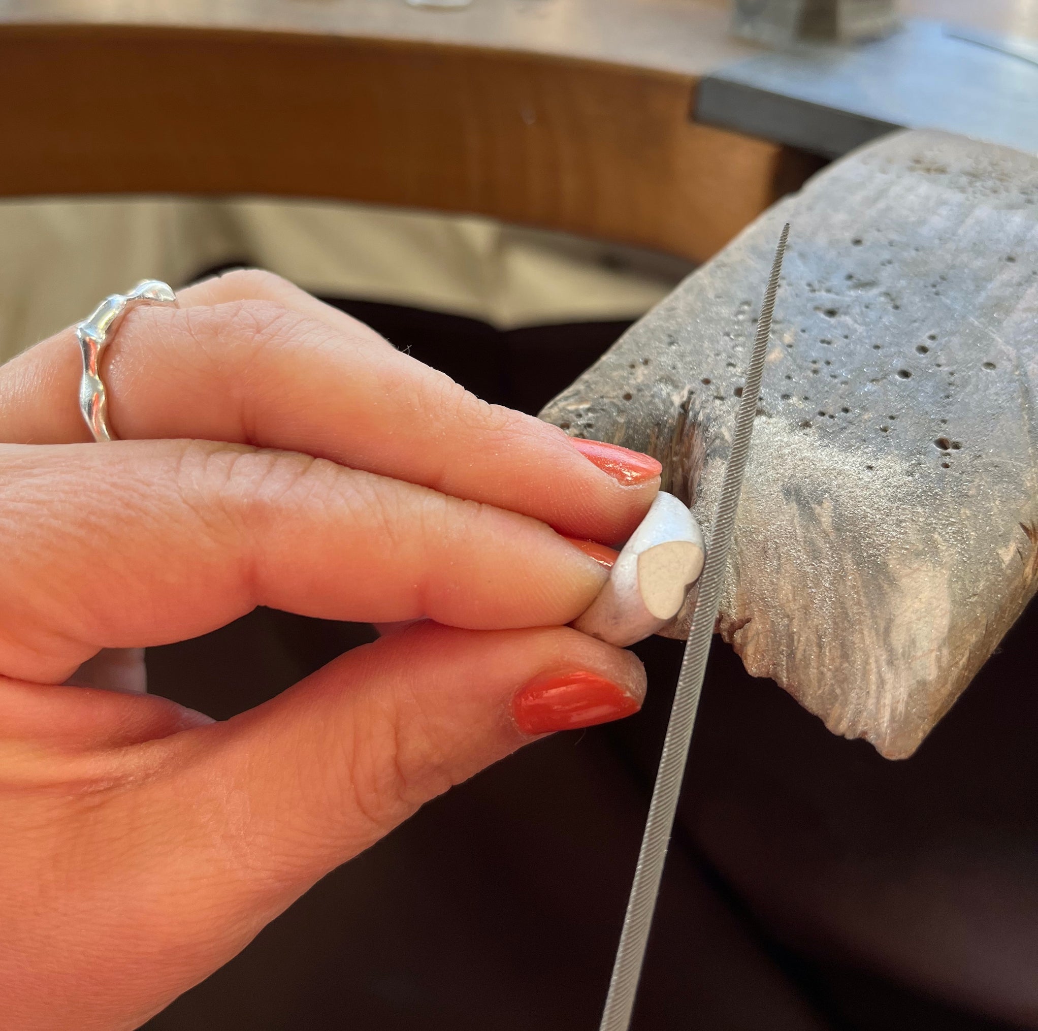 Frauen Hand feilt an einem Ring mit Herz Form