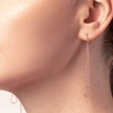 Frau mit Rosegold Ohrringe mit Kette und Anhänger in Tropfenform
